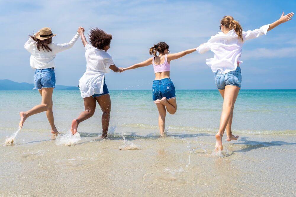 Imagem de várias amigas na praia. Elas estão celebrando o Dia da Amizade.