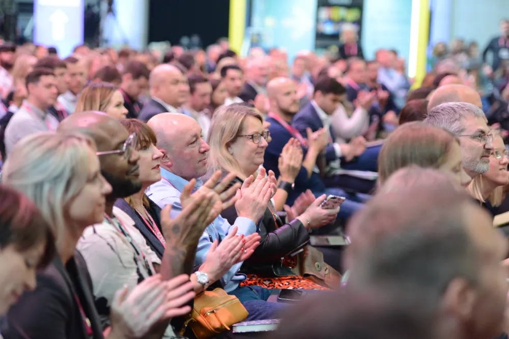 Imagem de pessoas assistindo uma palestra e batendo palmas.