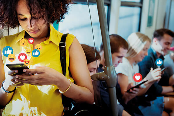 mulher em primeiro plano, no transporte público, utilizando o smartphones, com pessoas ao fundo também usando o celular
