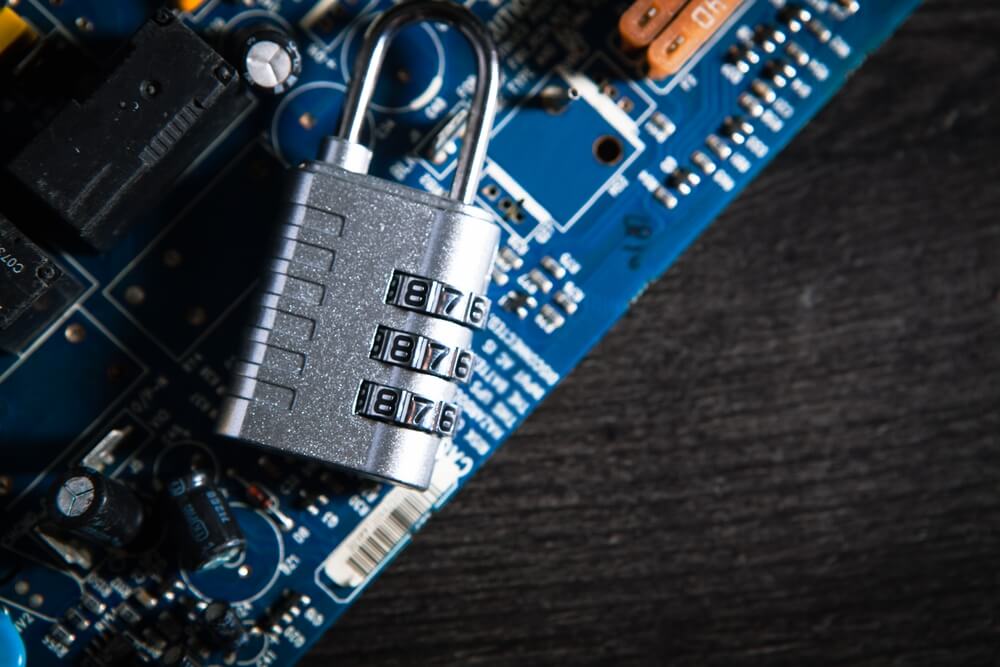 Imagem de um cadeado com senha em cima de uma placa de circuito, representando a segurança da informação.
